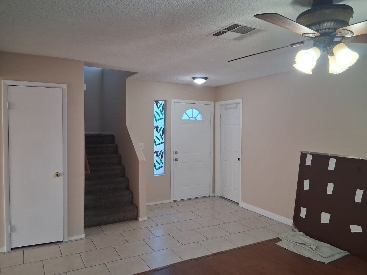 Entry hall with a ceiling fan, tile floor and stairs