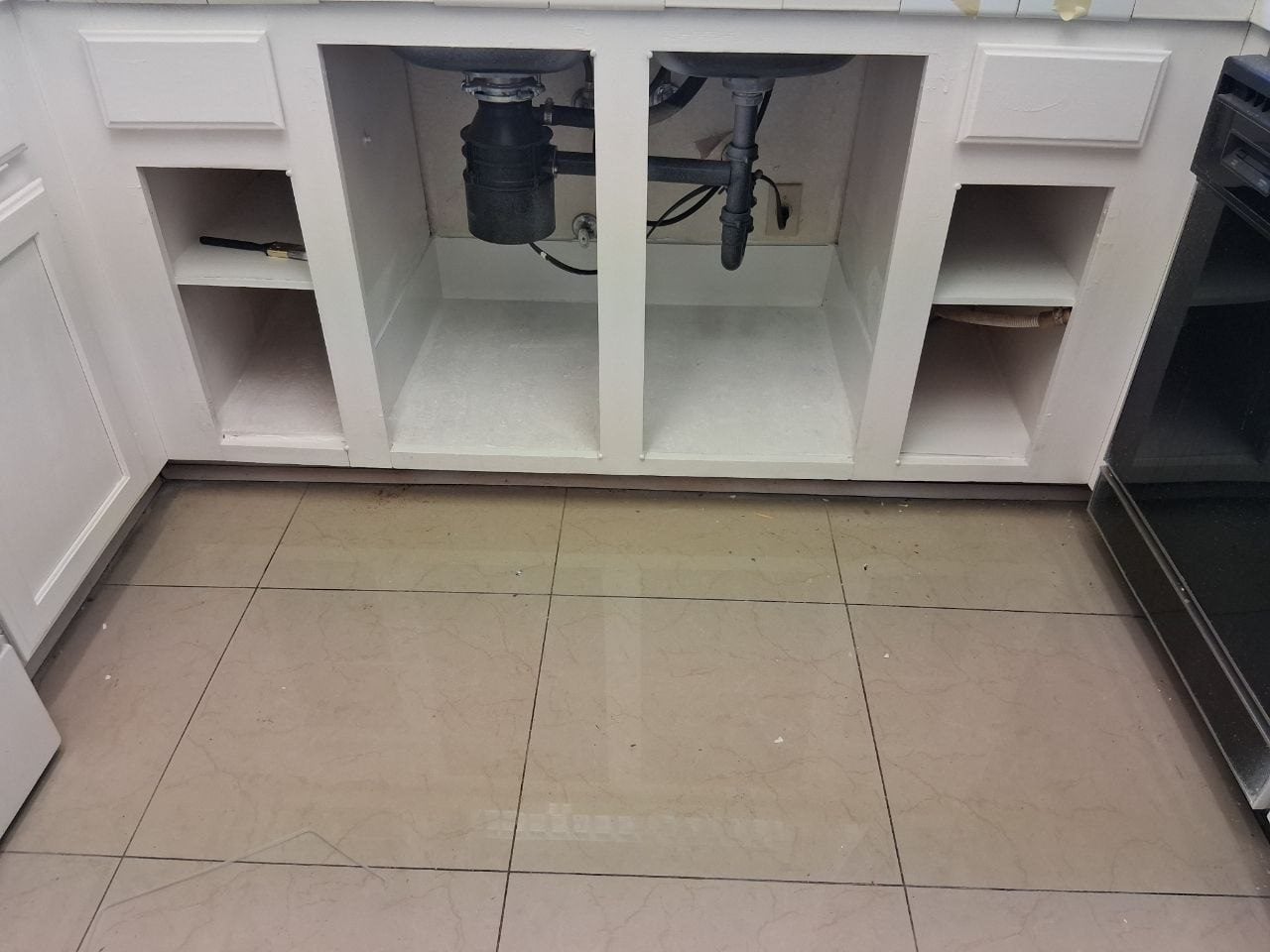 Kitchen sink cabinet opened up with new plumbing under the sink