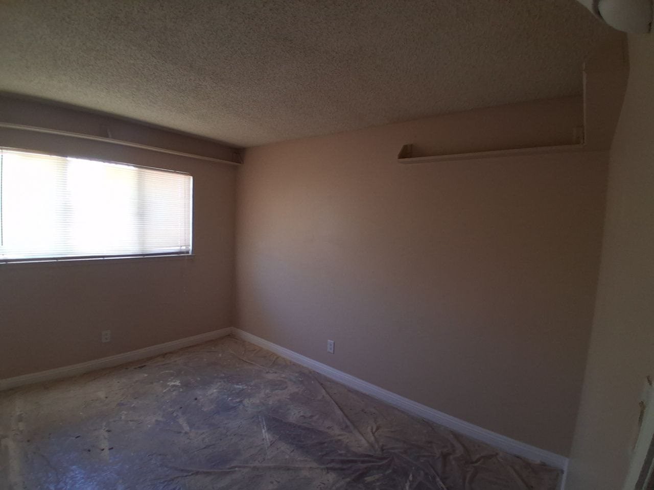 Empty bedroom with the floor covered and walls prepped for paint