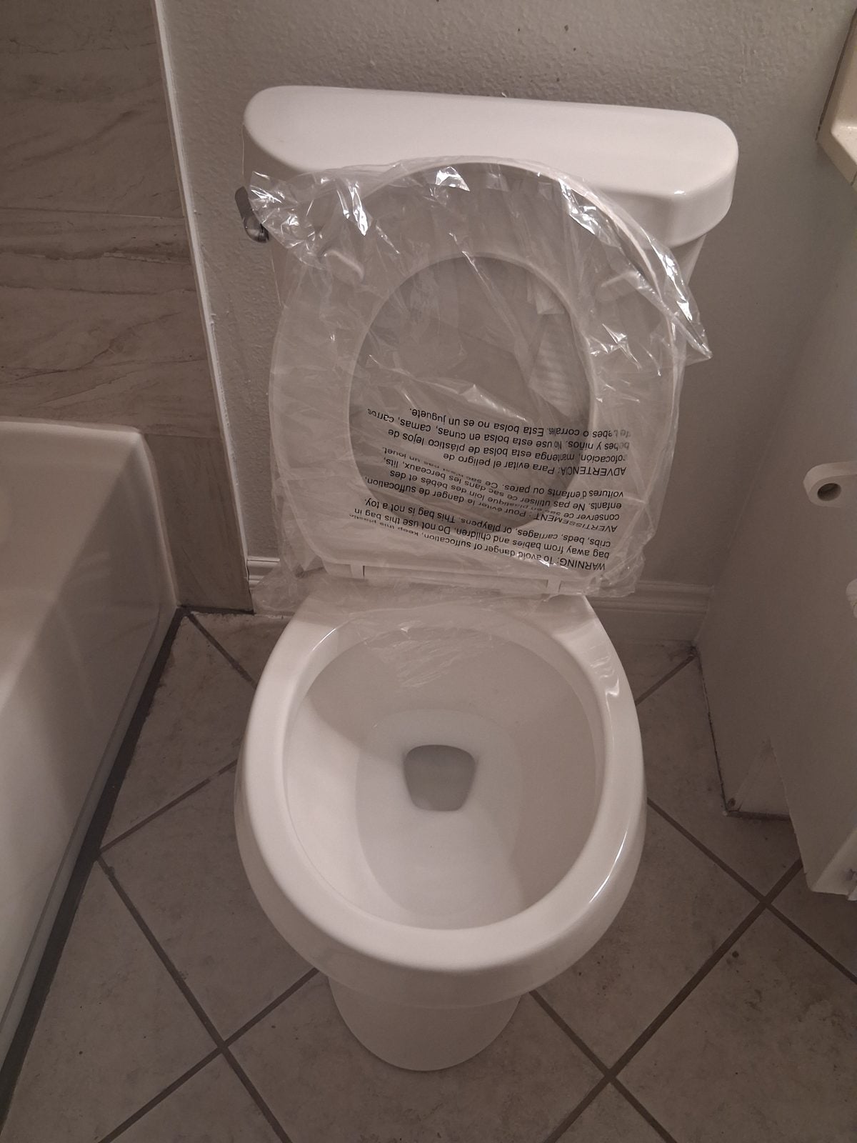 Newly installed toilet with the protective wrap still on the seat